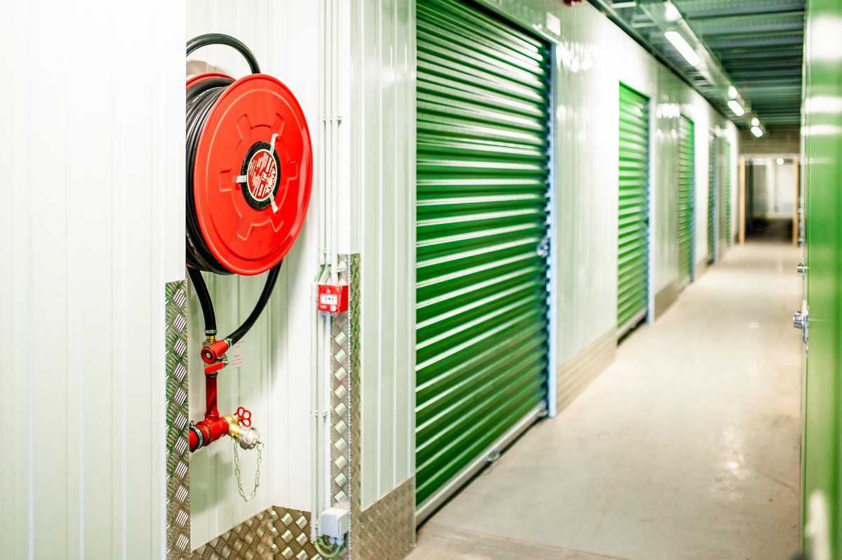 Flexistock interior - clean, secure self storage facility with green storage unit doors and a fire hose reel.